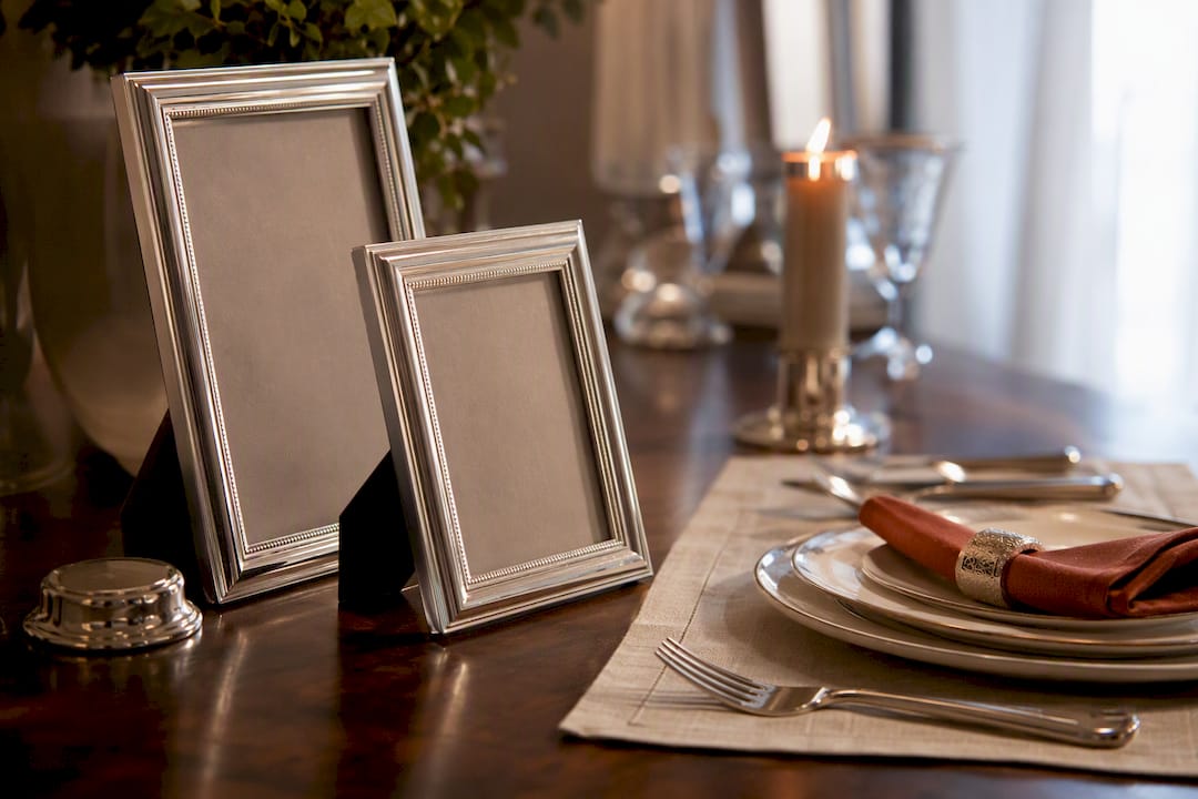 Silver-rimmed frames beside anniversary tableware
