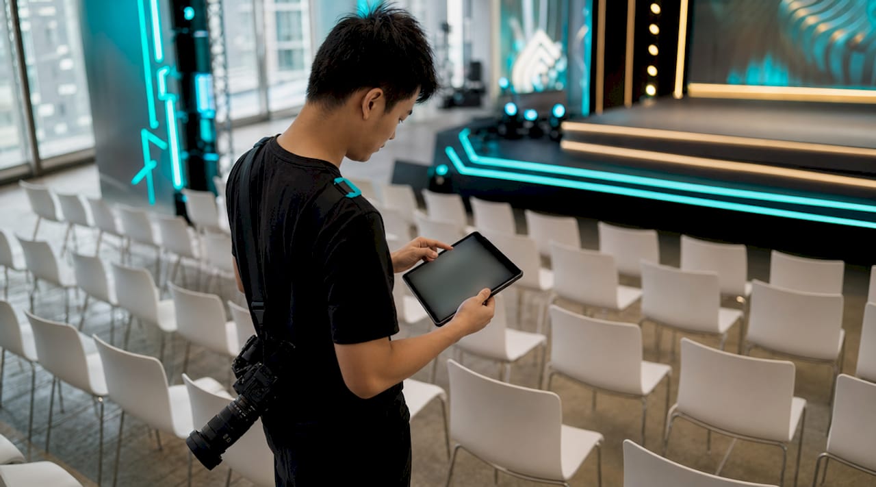 Person using a tablet in a row of white chairs at a modern event venue