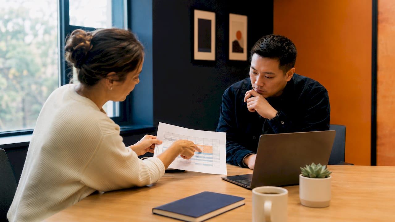 Hands pointing at RACI matrix document in meeting