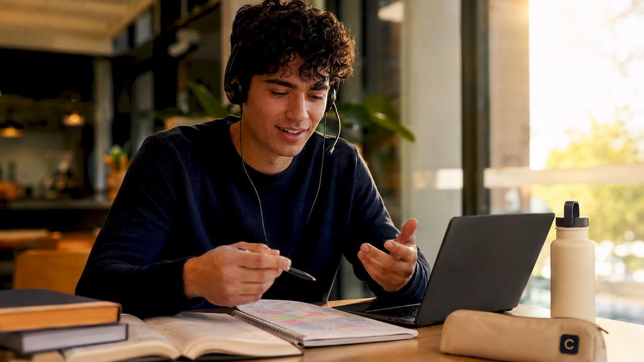 Student using voice chat with headphones and notes