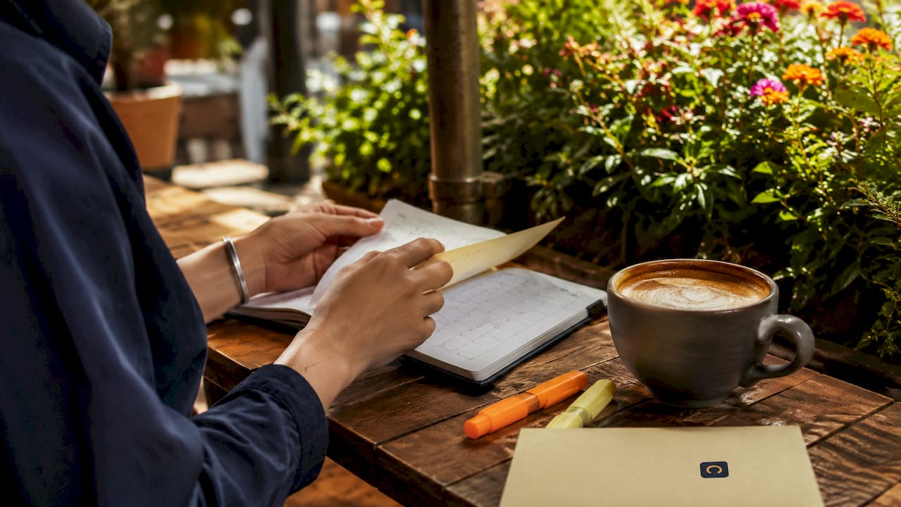 Hands holding phone and planner on café table