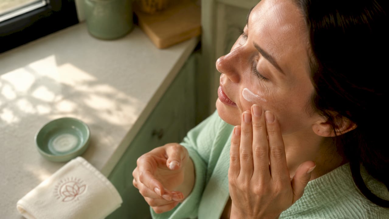 Close-up of hands applying moisturizer to facial skin