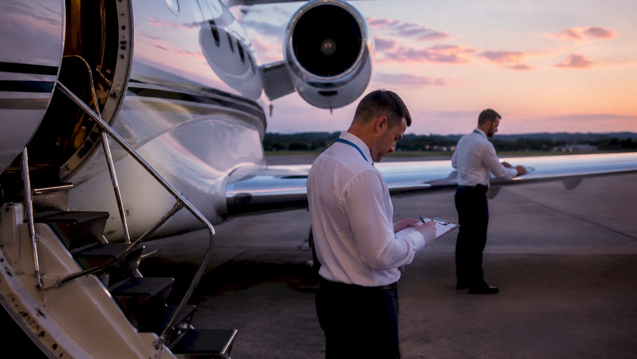 Private jet parked with ground crew performing checks