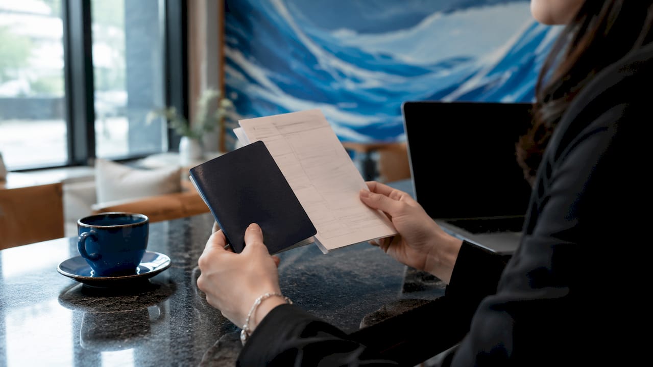 Close-up of hands holding passport and manifest
