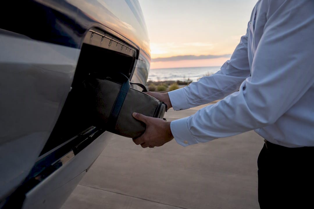 Hands loading luggage into private jet compartment