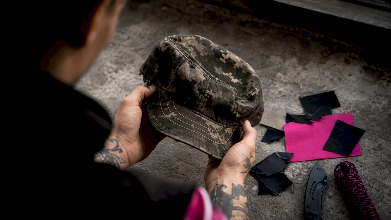 Hands holding embroidered Army cap on desk