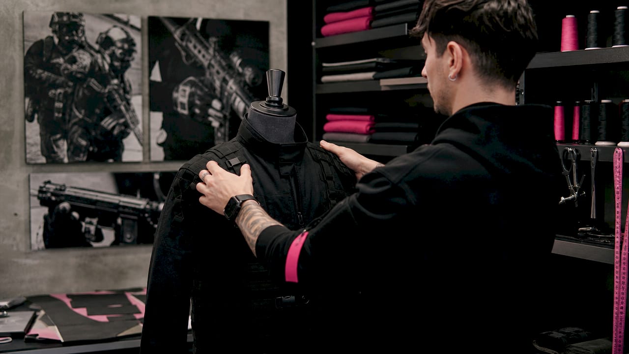 Hands adjusting tactical jacket on mannequin