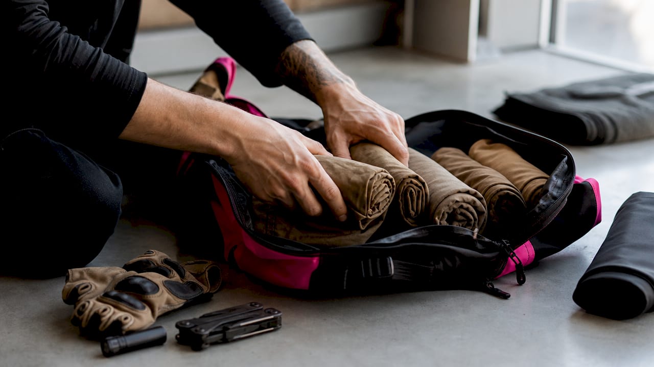 Hands packing military undershirts into backpack