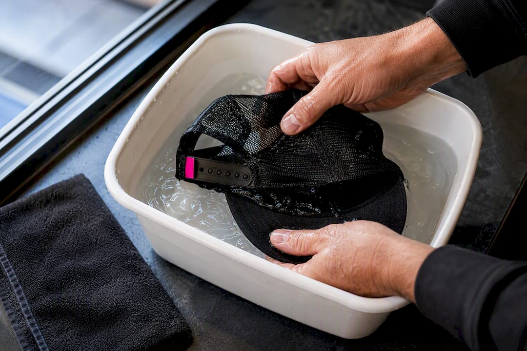 Hands gently washing a hat mesh panel