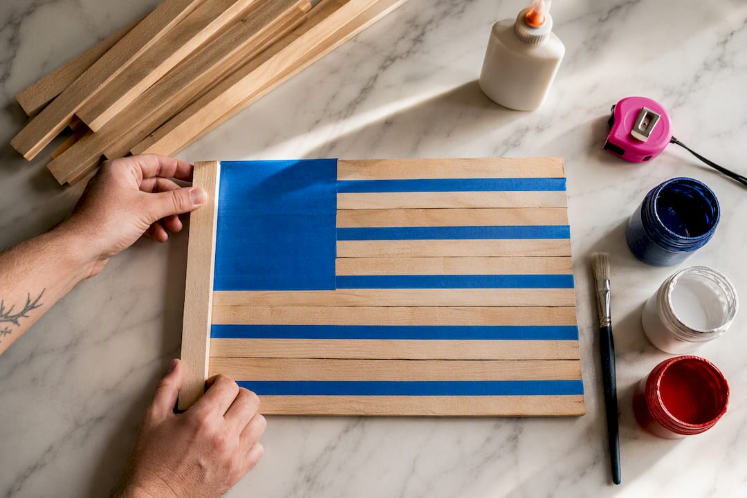 Hands assembling wooden shims for patriotic flag