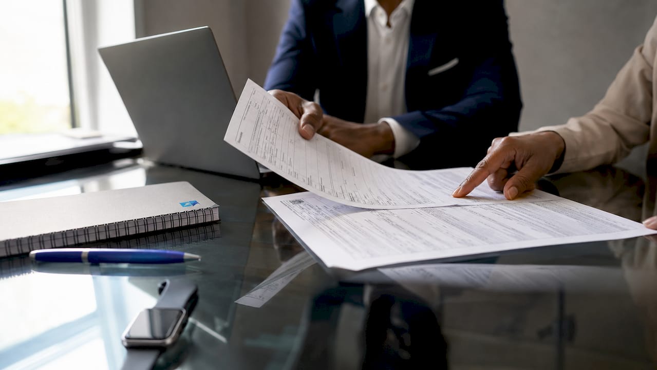 Hands cross-verifying financial documents on table