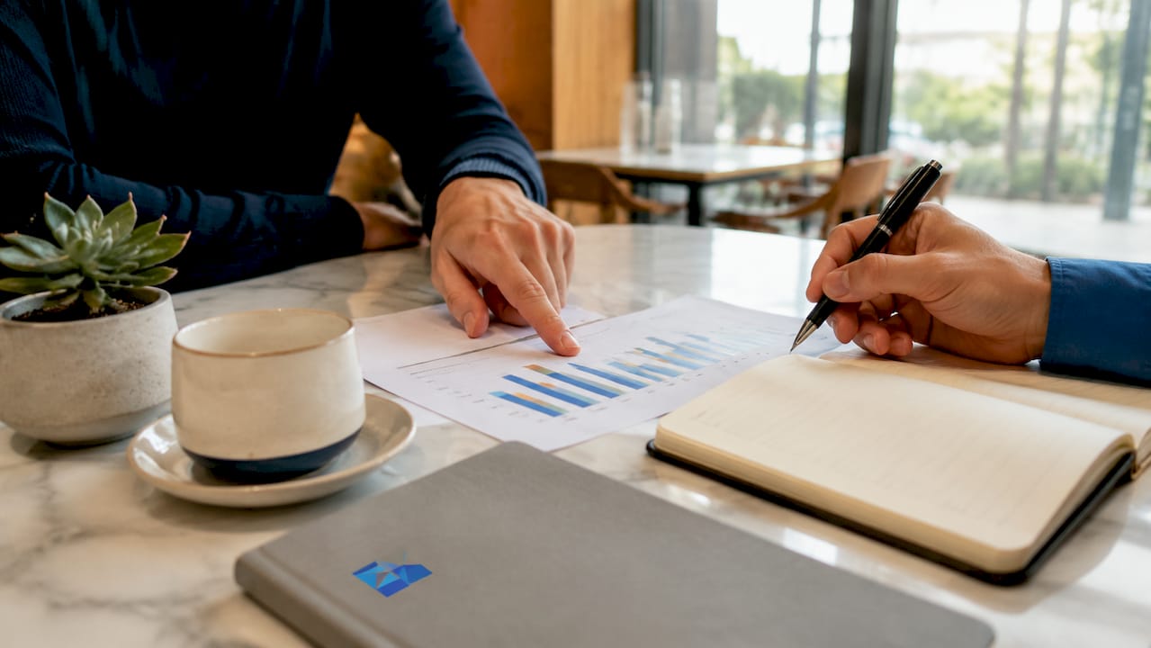 Overhead view of hands reviewing business financial graphs