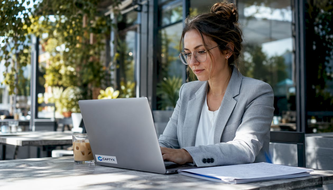 Woman working on laptop at outdoor cafe patio