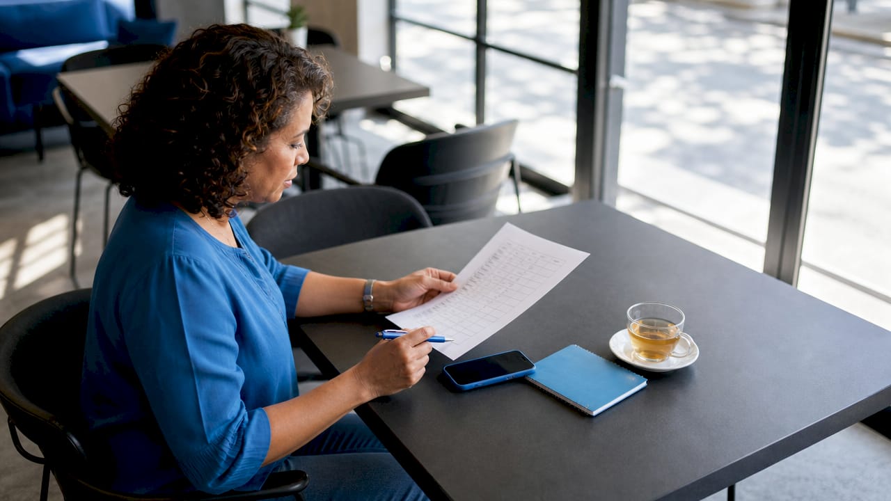 Woman reviewing cleaning checklist at kitchen table
