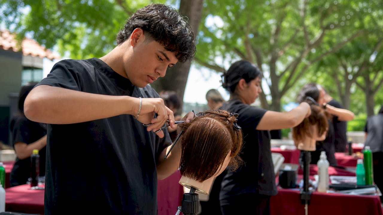 Student practicing haircut on mannequin head