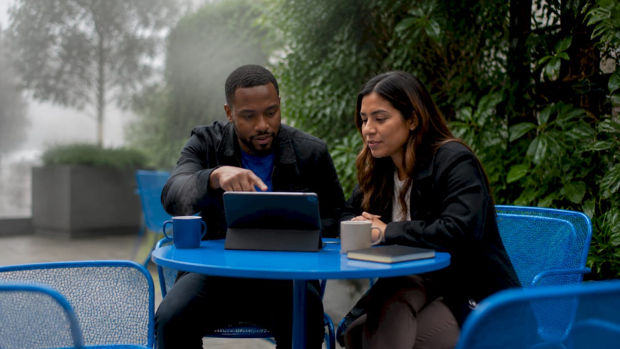 Two colleagues reviewing async email batches in café