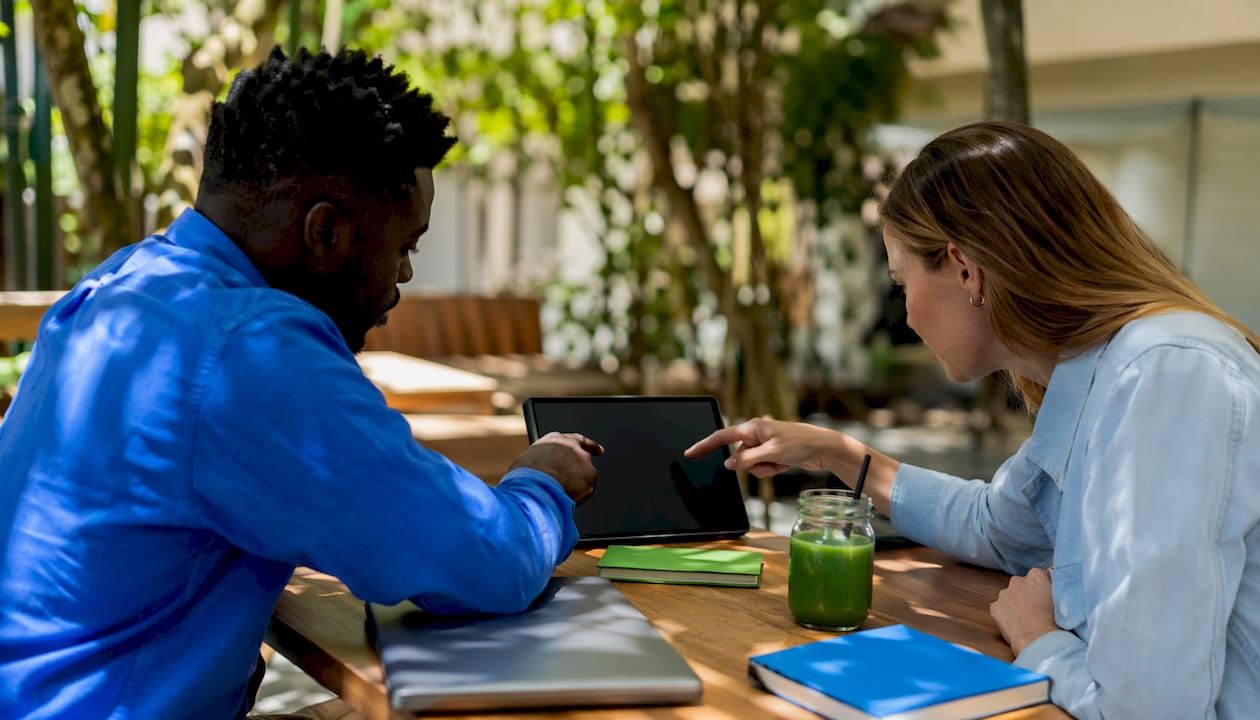 Collaborating hands pointing at tech devices