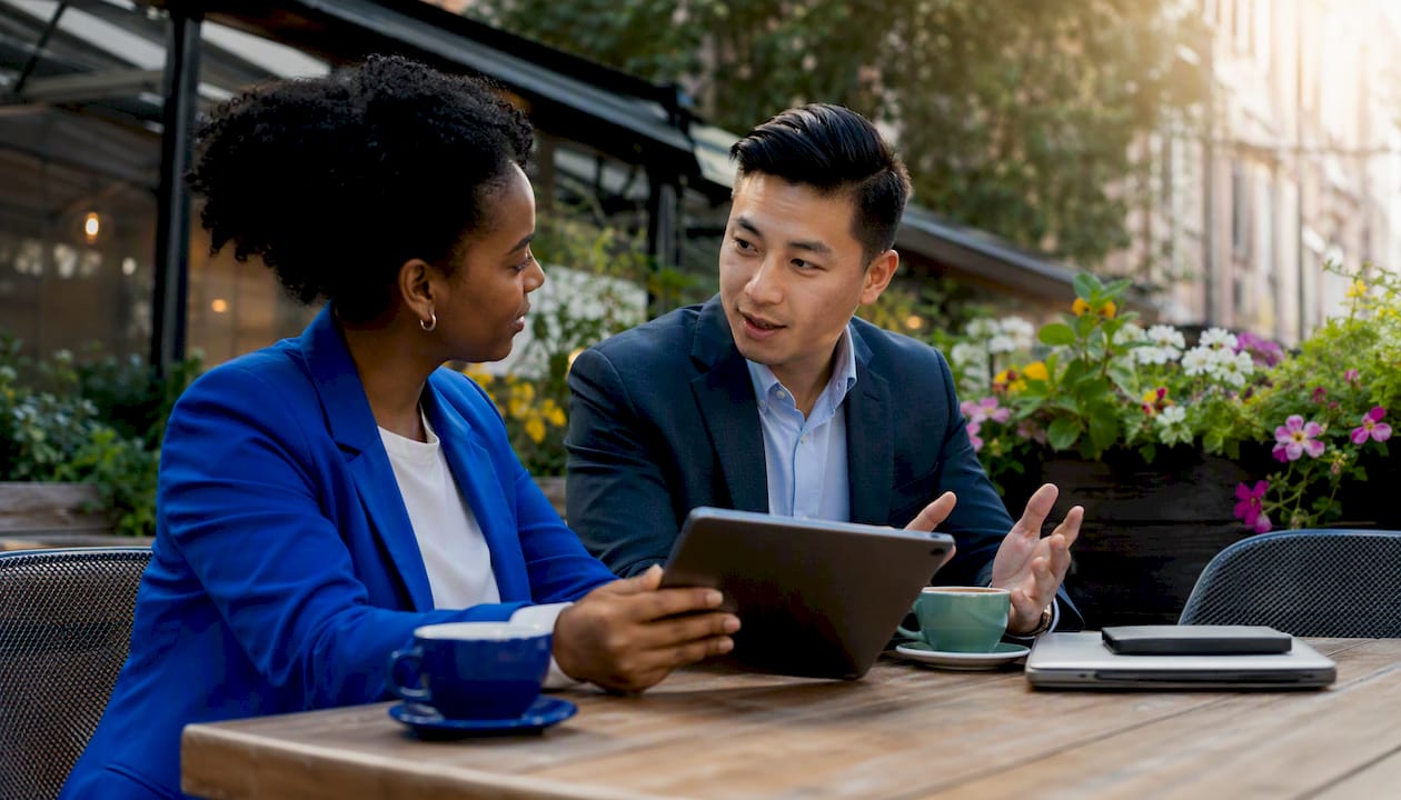 Coworkers discussing with smartphone in office kitchen