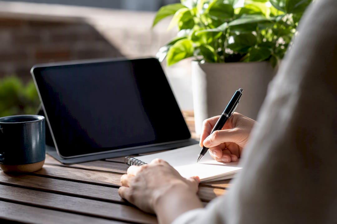 Hand holding pen near digital tablet and clock