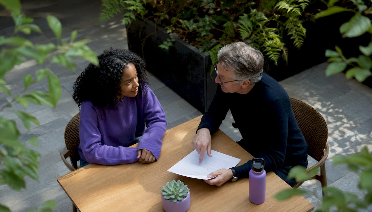 Mentor guiding new hire with printed SOP