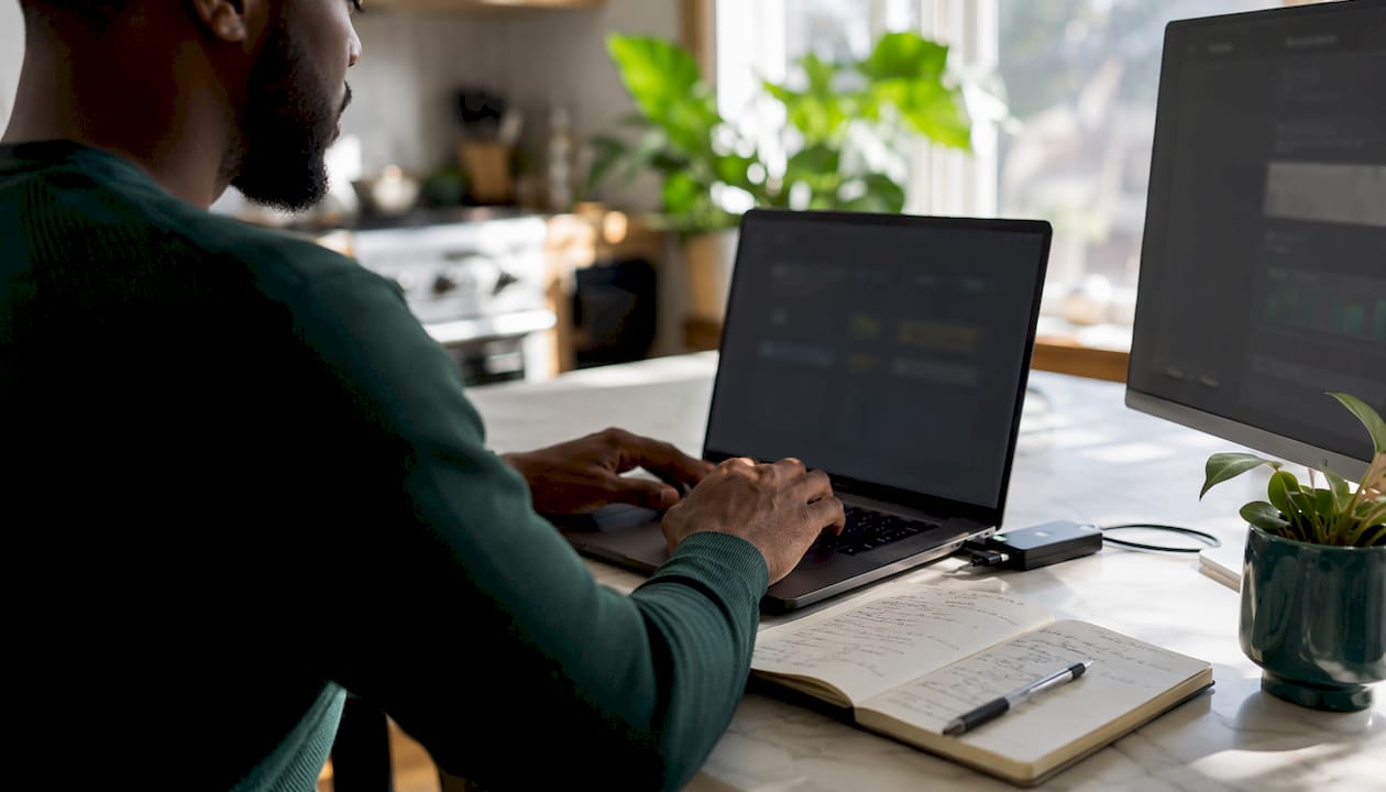 Hands typing with sales tools on laptop and notes
