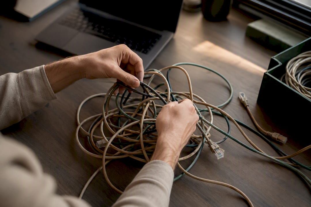 Hands untangling network cables on taupe desk