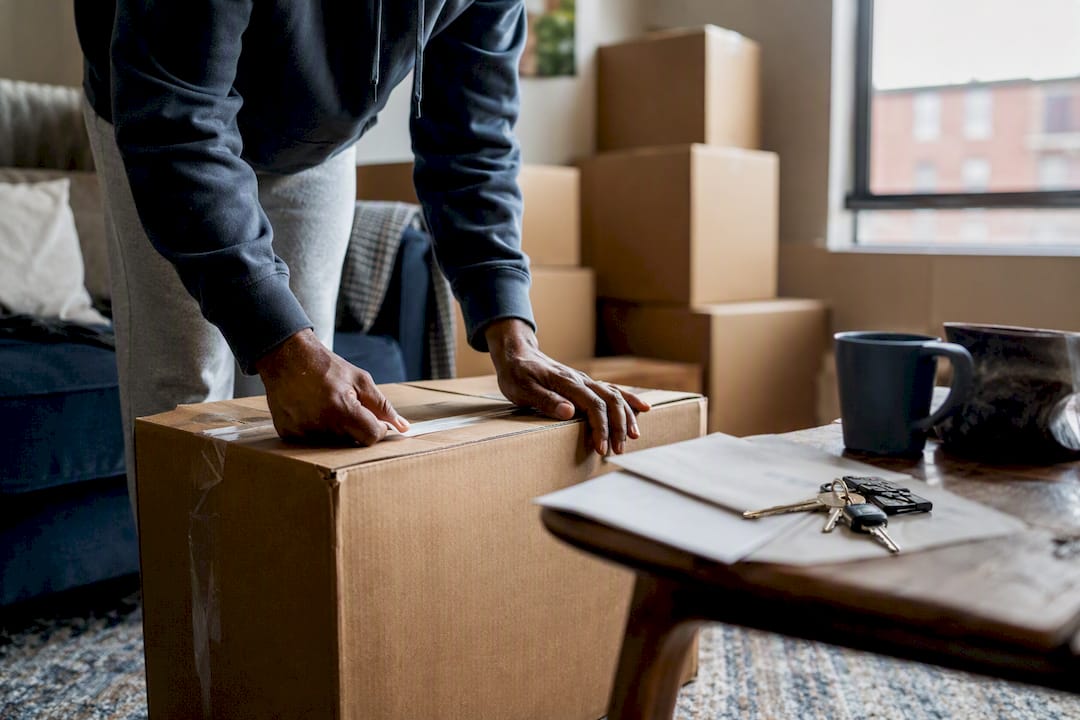 Hands taping moving boxes near home keys