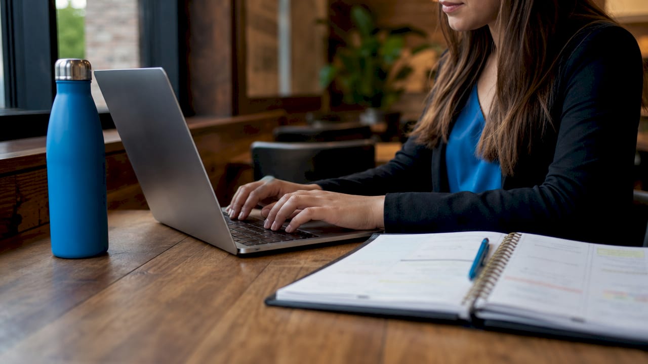 Hands typing on laptop amid real estate materials