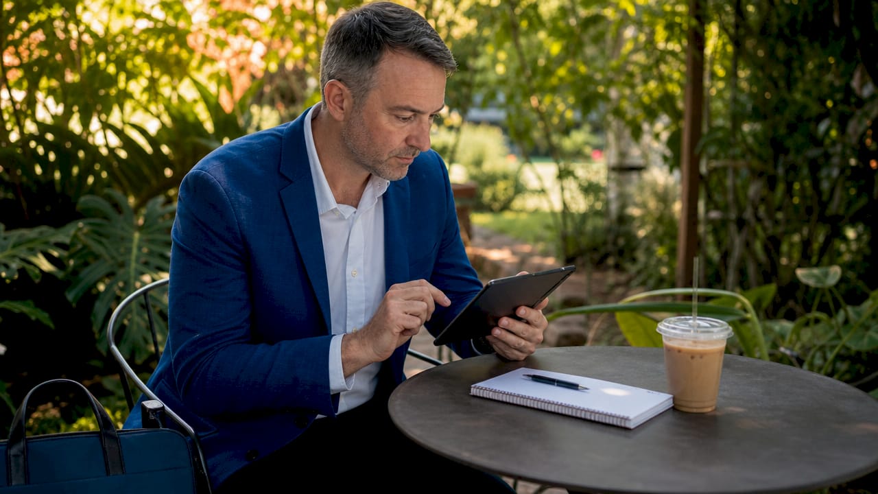 Real estate agent updating profile on tablet at café