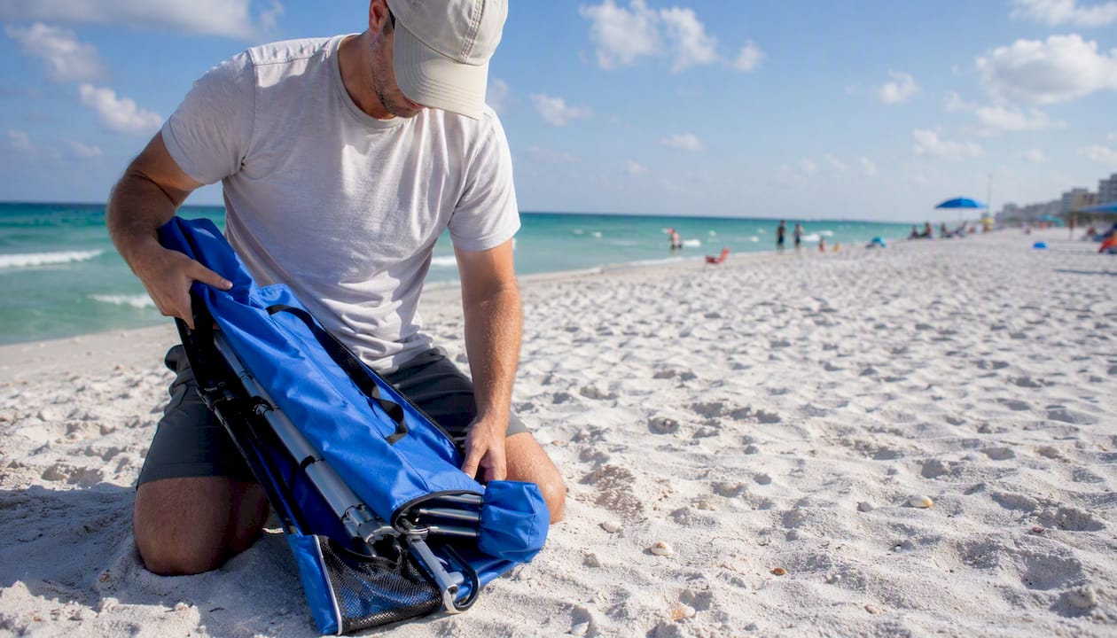 Hand adjusting beach umbrella strap on sand