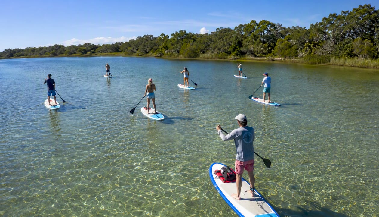 Group paddleboarders paddling on lagoon water
