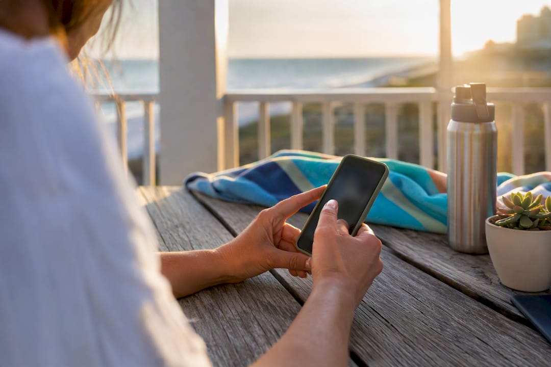 Hands using tablet at vacation rental porch
