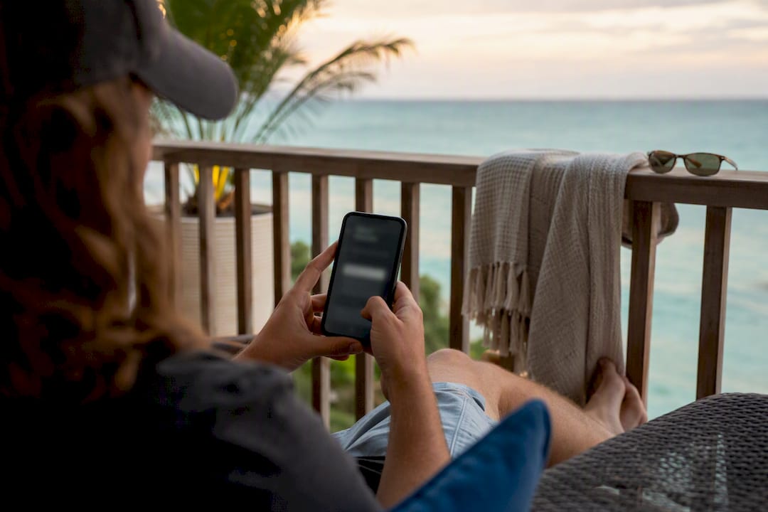 Traveler holding phone booking direct on rental porch