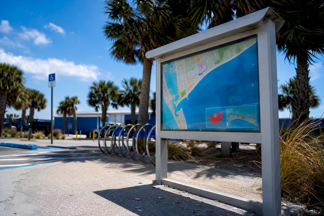 Beach parking area map kiosk with bike racks nearby