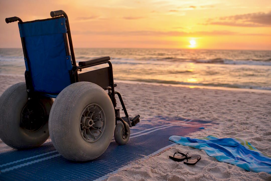 Beach wheelchair on the sand next to access mat
