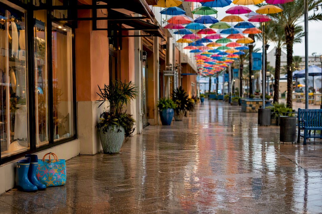 Pier Park covered walkway in rain with umbrellas