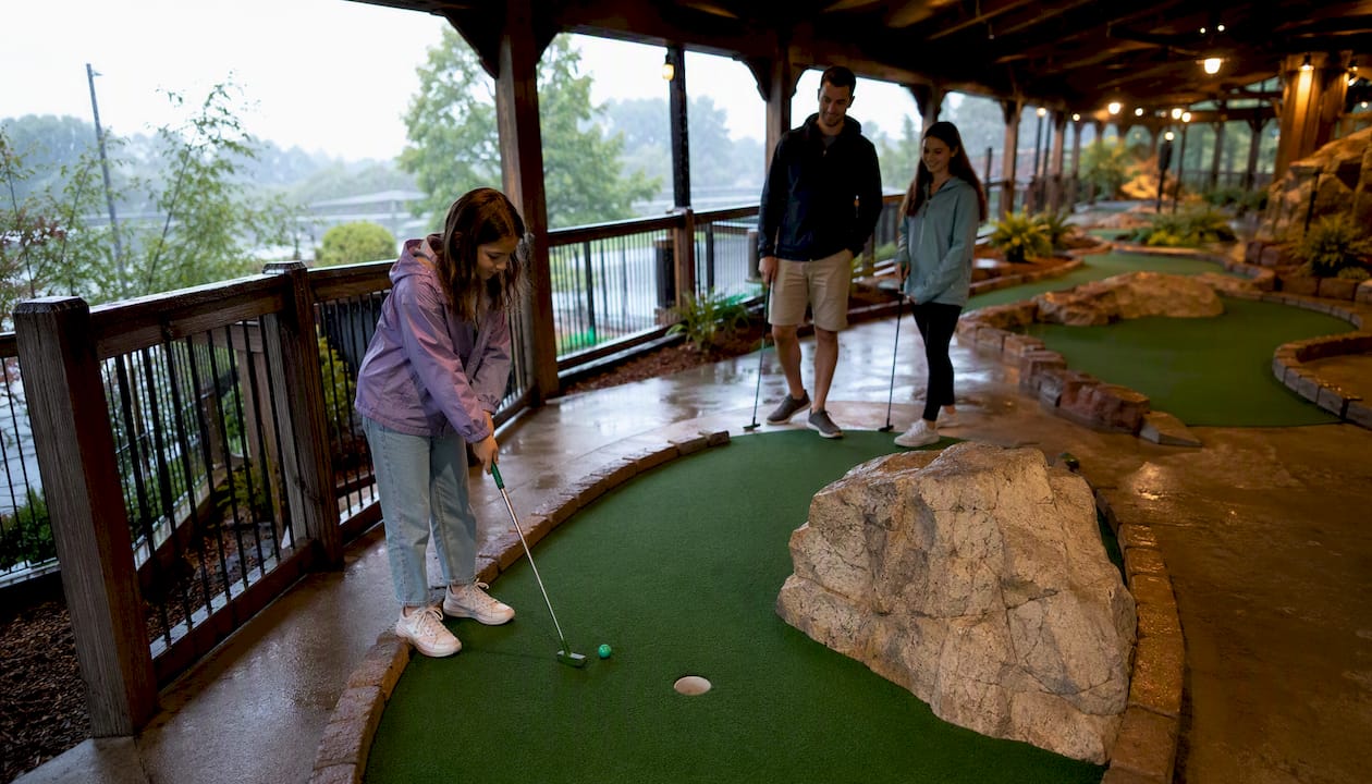 Family playing covered mini golf