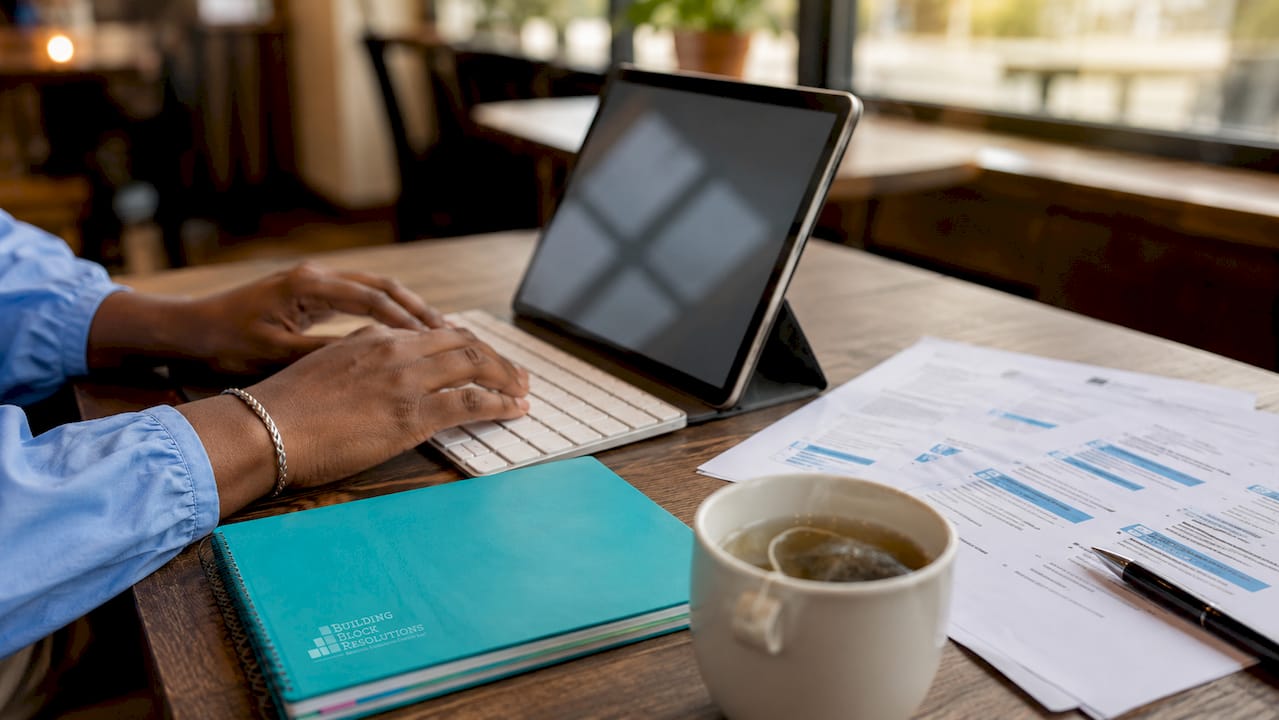 Close-up hands typing with clinical resume pages