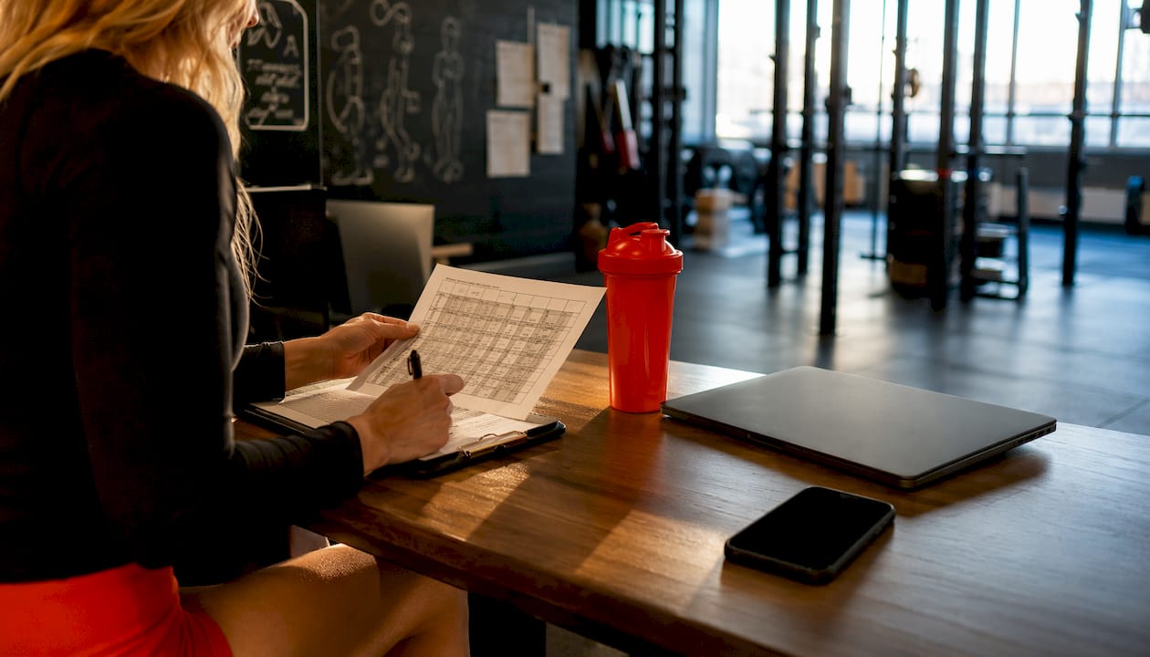 Overhead view of gym owner scheduling with clipboard