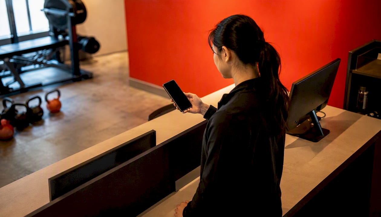 Hands holding smartphone switching gym family profiles