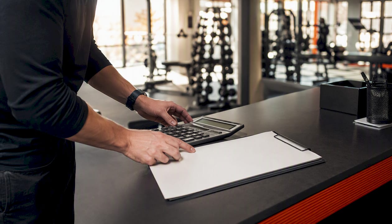 Hands organizing gym trainer schedule and payroll calculator