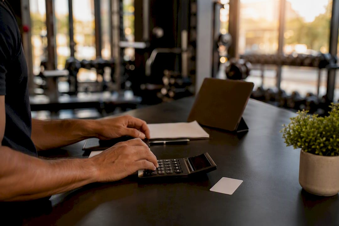 Hands calculating gym pricing in office