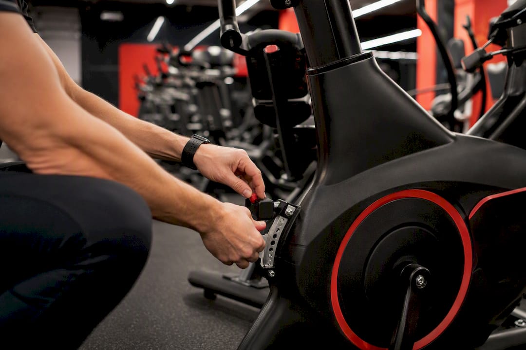 Technician inspecting treadmill belt in gym