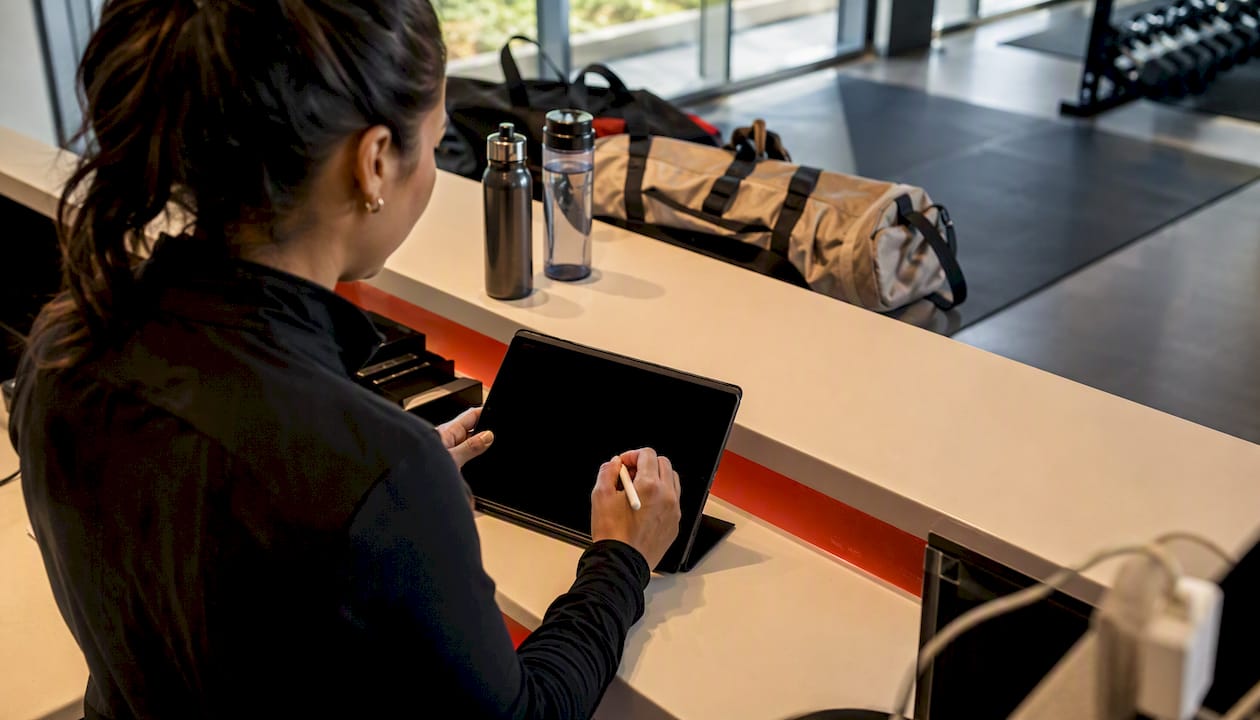 Hands booking gym session at front desk