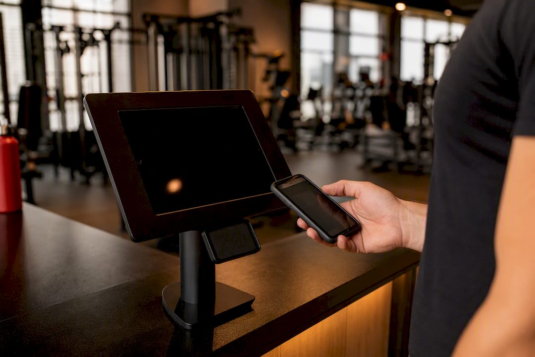 Hand scanning membership QR code at gym kiosk