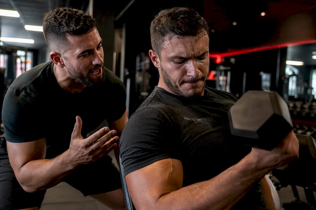 Member lifting weights motivated by trainer