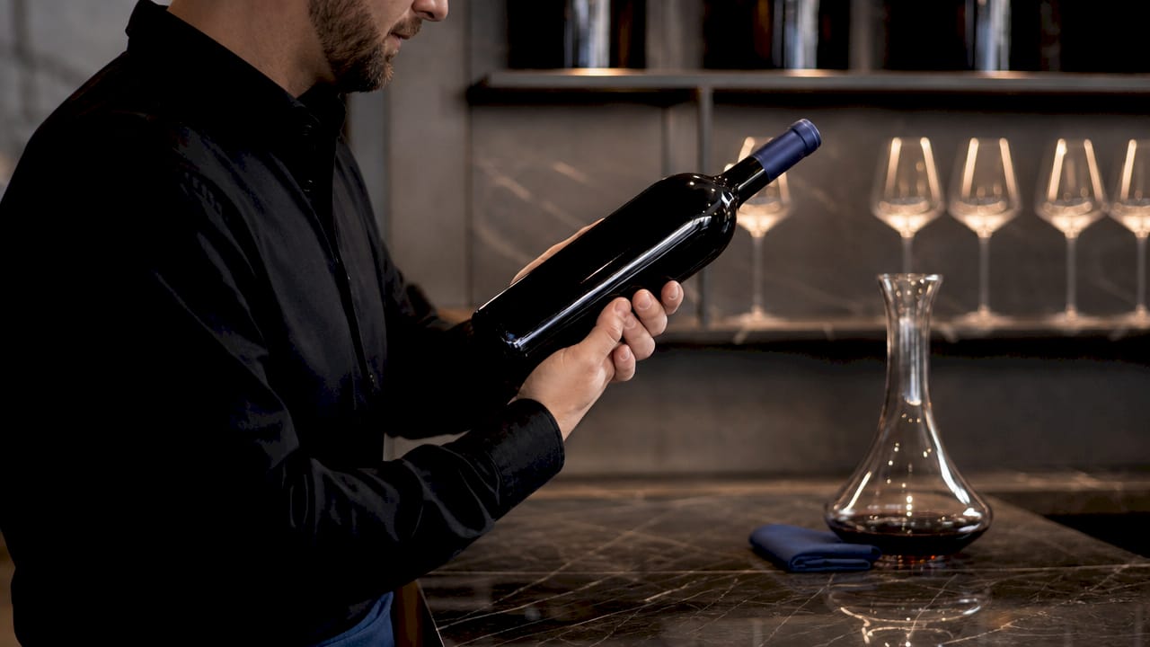 Hands comparing wine bottles in cellar