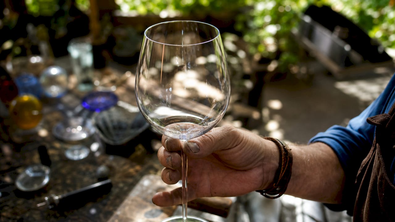 Close-up of fine rim wine glass held in artisan’s hand