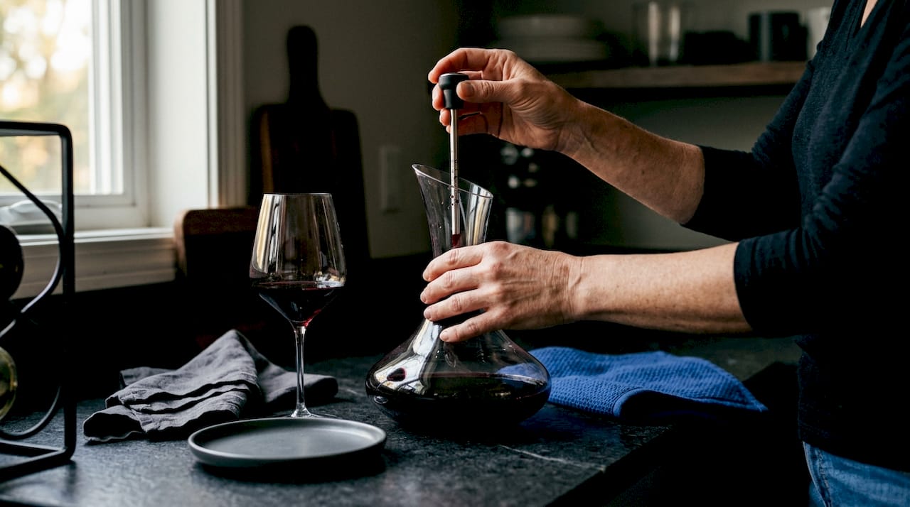 Woman measuring wine temperature with thermometer