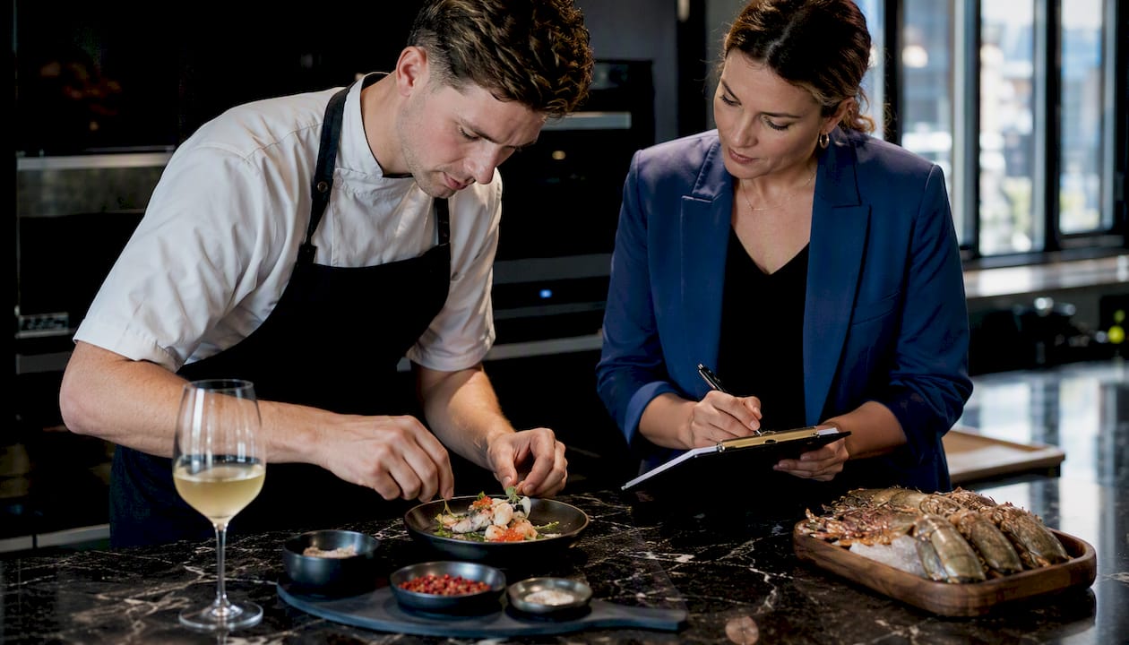 Chef and planner preparing tasting menu in kitchen